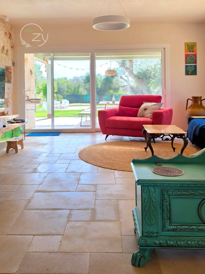 A red sofa and painted green chest by the sliding doors to the garden